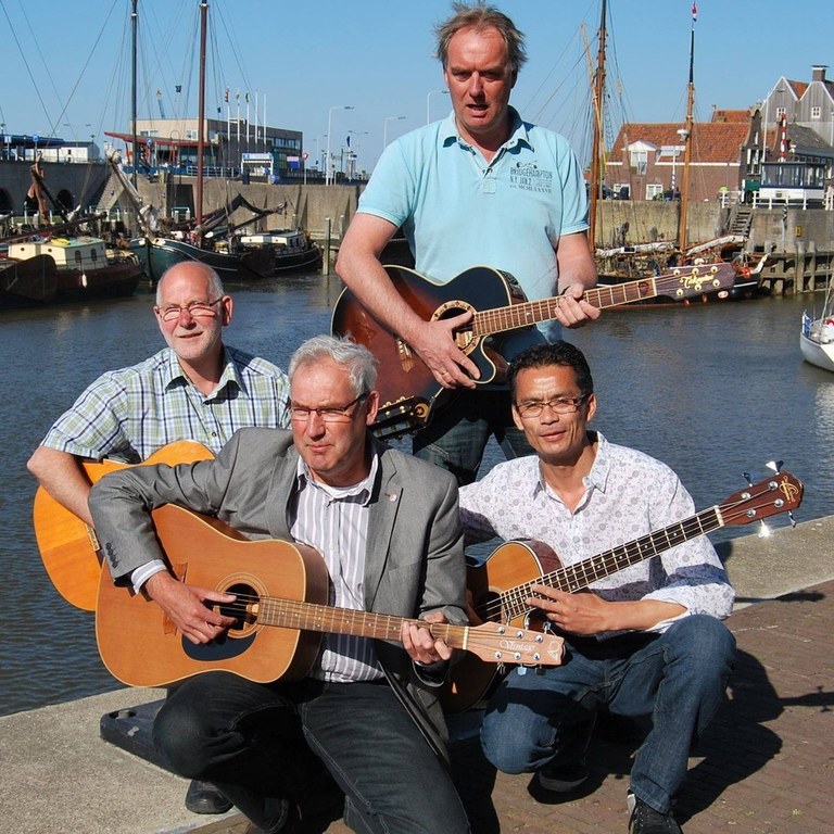 De vier leden van Just 4 Fun met gitaren bij de haven van Harlingen